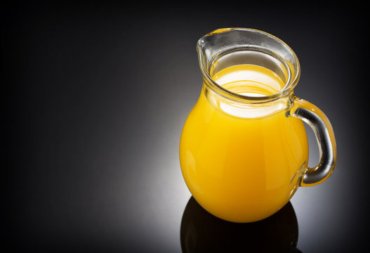 glass pitcher and orange juice on black