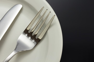 knife and fork at plate on black