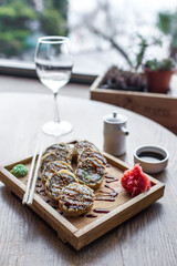 Baked sushi and rolls in a wooden plate with ginger and wasabi