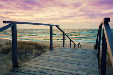 Wooden staircase with a handrail to the sea at sunset