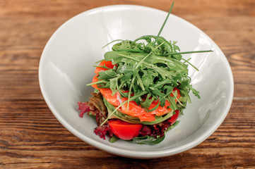 Fresh tartar with salmon, avocado, rucola and arugula on black white, close up