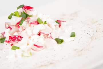Cottage cheese with radish and chives on a white plate
