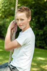 Young teenage boy swinging on a rope