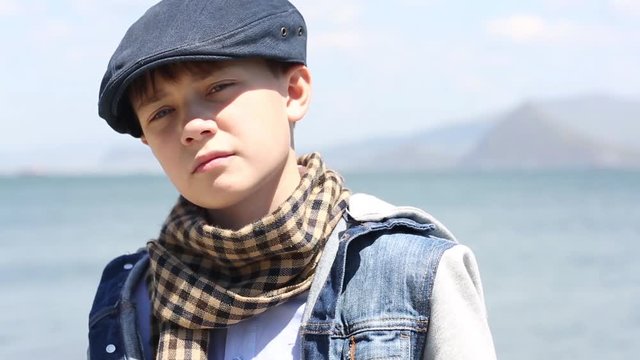 Pensive serious boy is looking forward and to the side of the sea
