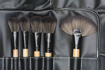 top view of makeup brushes on black leatherette