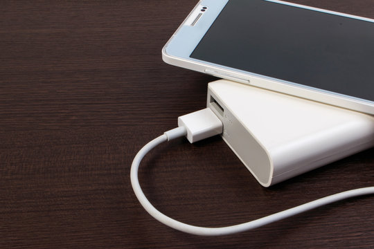 USB cable charger with energy bank on wooden table.