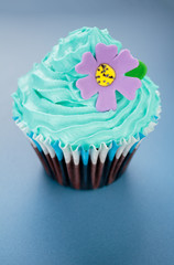 Cupcake with blue icing and purple flowe