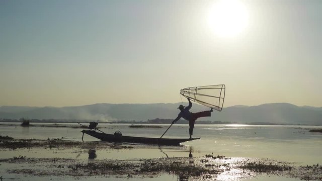 Myanmar travel attraction landmark - Traditional Burmese fishermen with fishing net at Inle lake in Myanmar famous for their distinctive one legged rowing style, 4k
