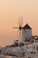 Sunset over white windmills in  town of Oia and panorama to Santorini island, Thira, Cyclades, Greece