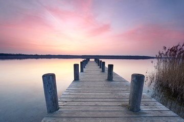 einsamer Steg aus Holz am See - morgens zum Sonnenaufgang