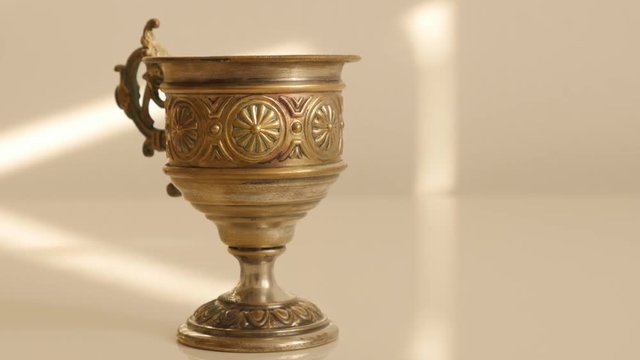 Ancient handmade goblet of brass on white surface 4K 2160p UltraHD tilting footage - Holy grail on white background slow tilt 4K 3840X2160 UHD video 