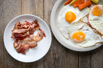 Bacon and Fried egg placed on a wooden table view from top