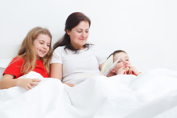 mom having fun reading a book in bed for her childs before sleep