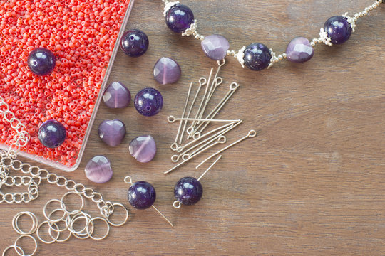 Beads and tools on wooden floor flat lay
