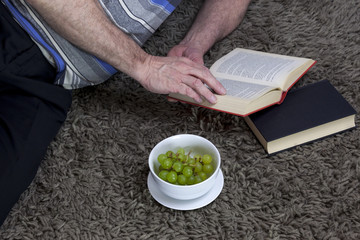 Man laying on a shaggy grey rug reading a book