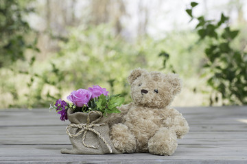 Teddy bear with flower vase on the wooden floor .