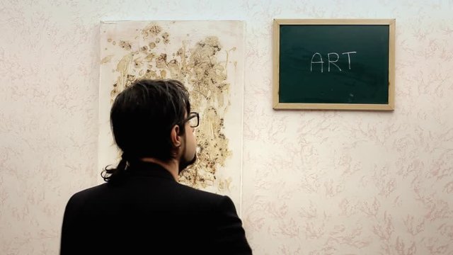 A critic at an art exhibition adds the letter F to the word "Art" near an abstract painting. Funny scene.