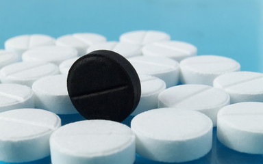 a black tablet pill among of scattered white ones, cure, medicine, doping