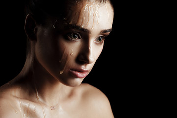 Beauty Portrait of Young Woman with Strobing Makeup Liquid on Face. Wet Body Effect. Strobing...