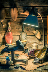 Vintage shoemaker workplace with shoes, laces and tools