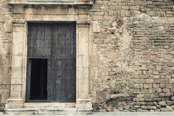 Black door gate on a ruined stone wall 