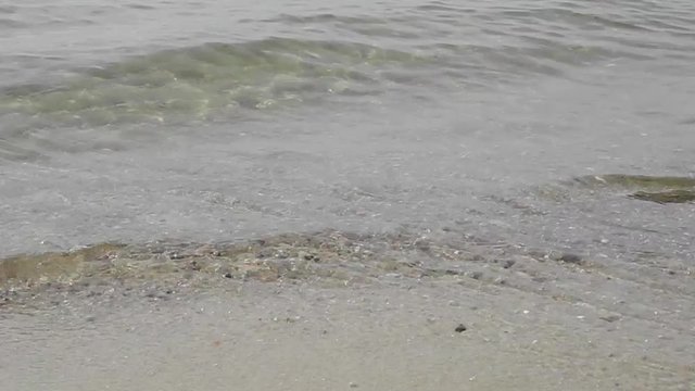 kleine Wasserwellen am sandigen Flussufer im Sonnenlicht