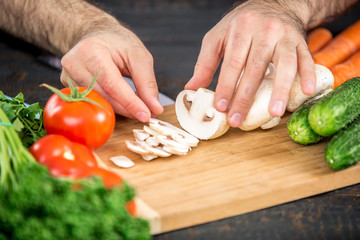 Male hands cutting vegetables for salad