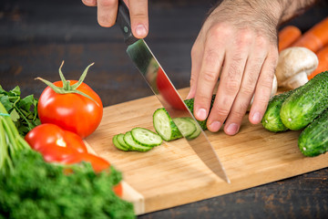 Male hands cutting vegetables for salad