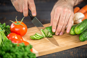 Male hands cutting vegetables for salad