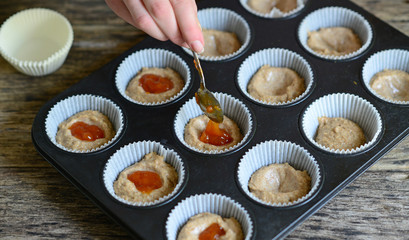 Woman hand prepare healthy muffins with jam