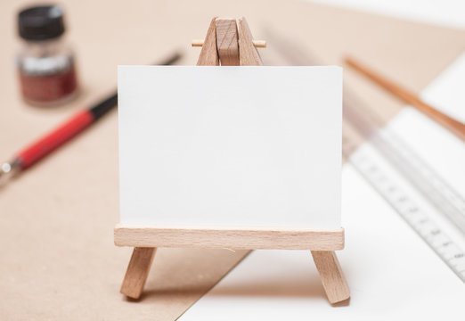 mini easel with canvas on table with artistic tools