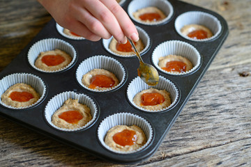 Woman hand prepare healthy muffins with jam