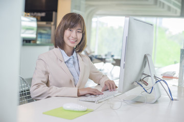 Attractive asian business woman working on computer in workplace