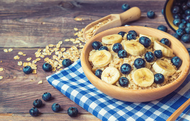 Oatmeal with blueberries and banana in wooden bowl