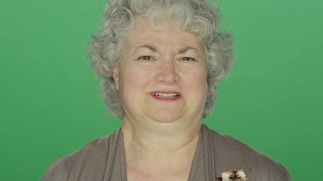 Older woman smiling, on a green screen studio background