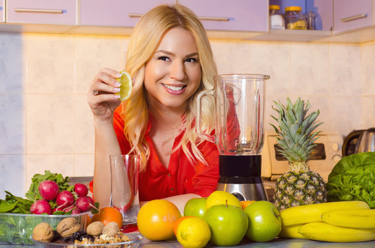 Happy smiling girl squeezing lemon, making juice in her kitchen / healthy lifestyle concept