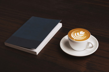Side view perfect cappuccino with tree milky foam art on top near business note book isolated on red wooden table in meeting room or cafe shop in coffee break time