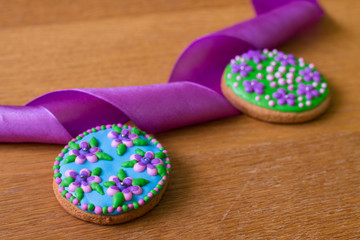 Gingerbread with flowers and purple ribbon on wood table. 