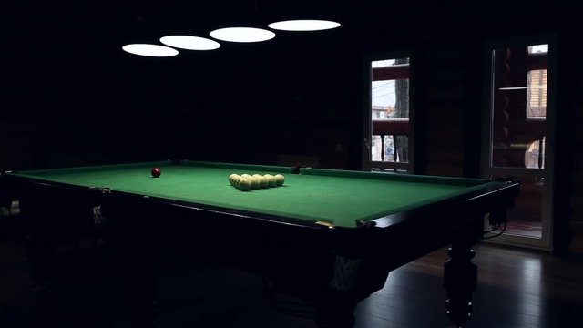 Billiards table and balls  illuminated with four round lamps
