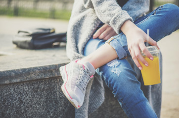 Young beautiful woman, sitting on the street , drinking smoothie.