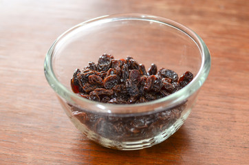 dry raisin in glass bowl on wood background