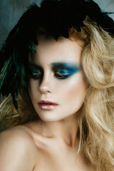 Fototapeta premium Beautiful girl in the image of bird with bright makeup, gold ha