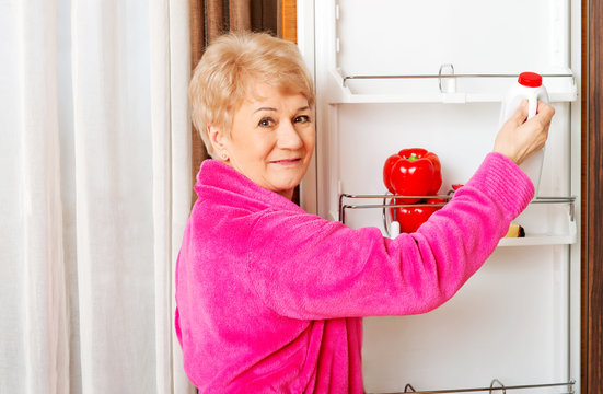 Senior woman taking a bottle of milk from fridge