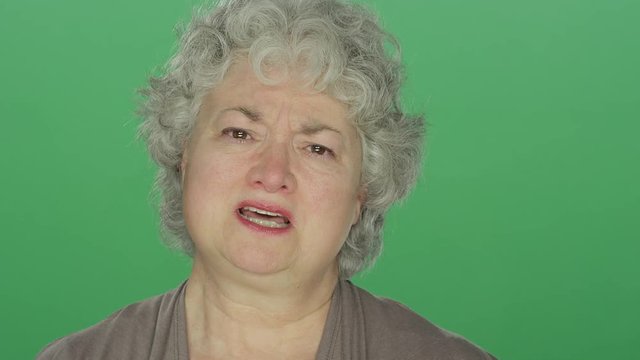 Older Woman Getting Teary Eyed And Upset, On A Green Screen Studio Background 