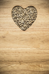 Heart shaped sunflower seeds on wood surface