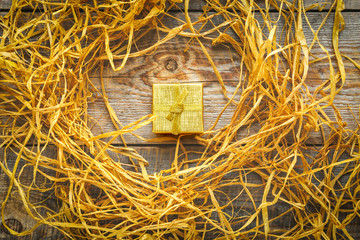 Golden gift box on wooden table with raffia or twine