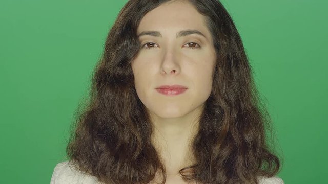 Young brunette woman staring, on a green screen studio background
