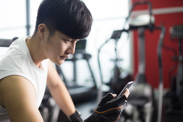 young handsome asian man using smart phone in modern gym