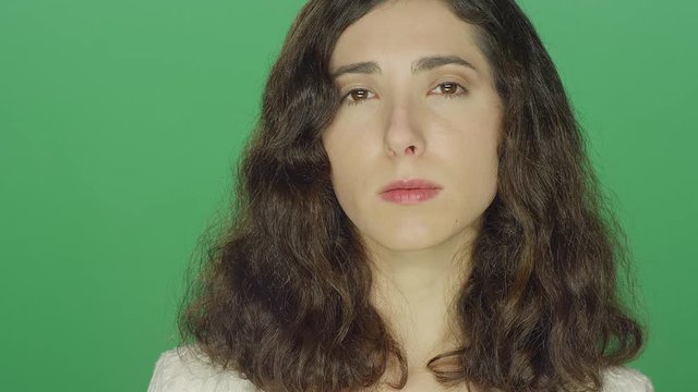 Young brunette woman smiling, on a green screen studio background 