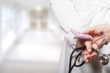 The doctor put his hands with stethoscope and money behind his b